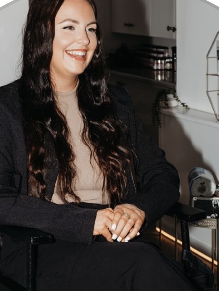 Jasmine Blundell, make-up artist, seated and smiling in her studio